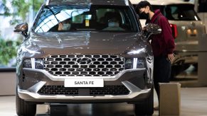 Customers wearing protective masks look inside a Hyundai Motor Co. Santa Fe sport utility vehicle (SUV) on display at the company's Motorstudio showroom