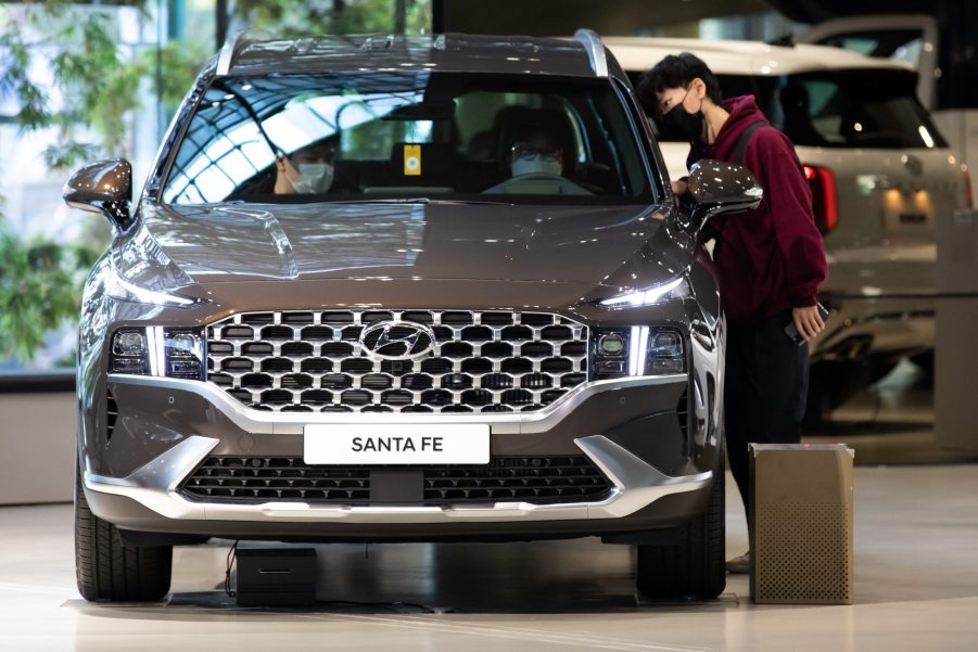 Customers wearing protective masks look inside a Hyundai Motor Co. Santa Fe sport utility vehicle (SUV) on display at the company's Motorstudio showroom