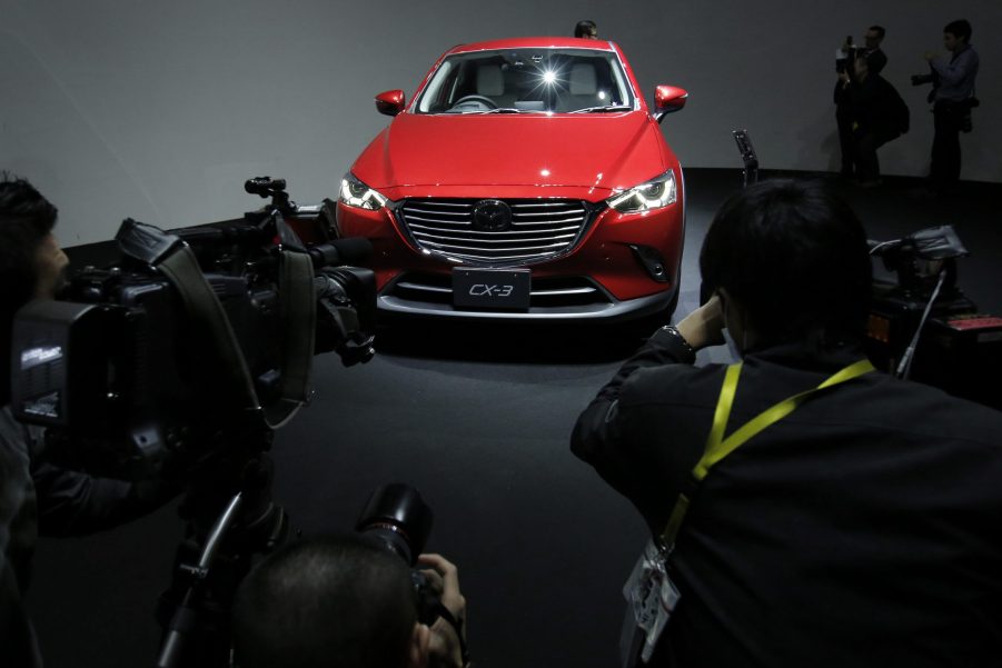 Members of the media take photographs and film videos of Mazda Motor Corp.'s new CX-3 compact crossover sport-utility vehicle (SUV) on display during a news conference in Tokyo, Japan