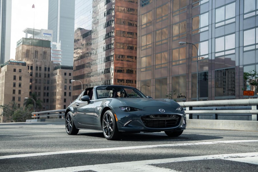 A Mazda MX-5 Miata driving down a city street.