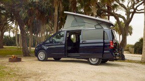 A navy-blue Mercedes-Benz Metris Weekender camper van parked in a beach park