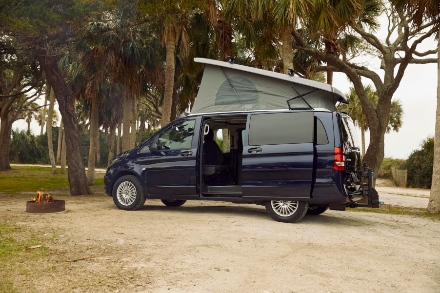 A navy-blue Mercedes-Benz Metris Weekender camper van parked in a beach park