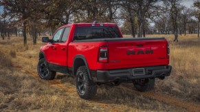 Red Ram 1500 Classic pickup truck driving down a dirt road lined with trees