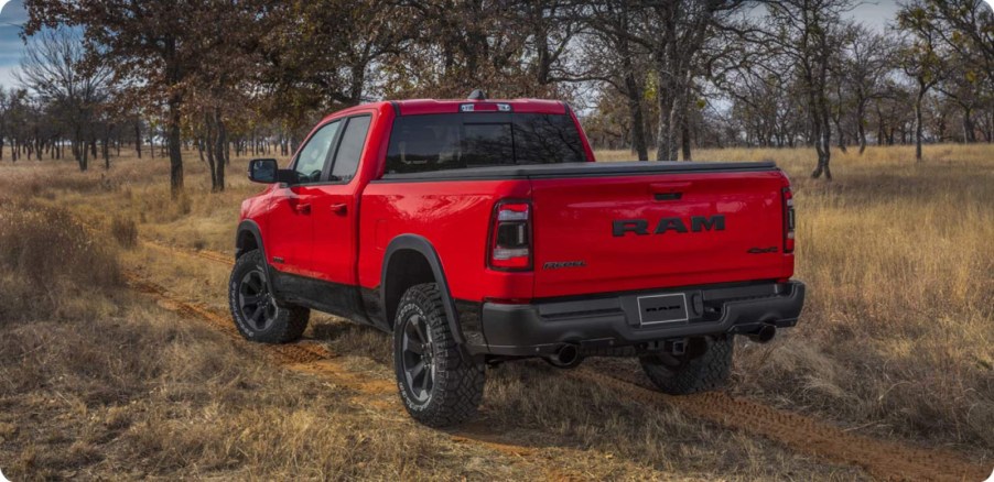 Red Ram 1500 Classic pickup truck driving down a dirt road lined with trees