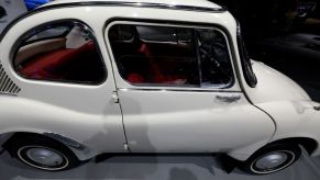 white Subaru 360 sedan on display at an auto show