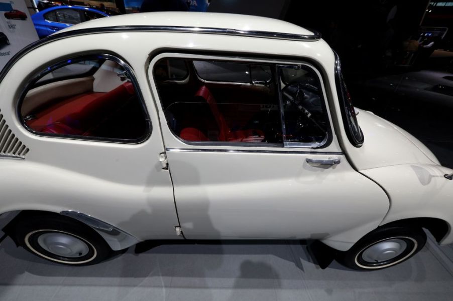 white Subaru 360 sedan on display at an auto show