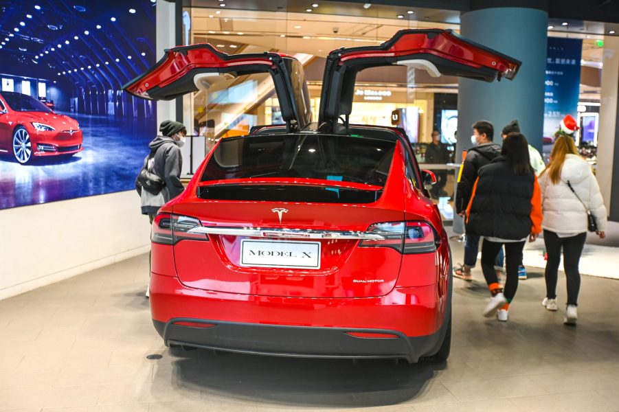 Customers watch a Model X vehicle at a Tesla flagship store