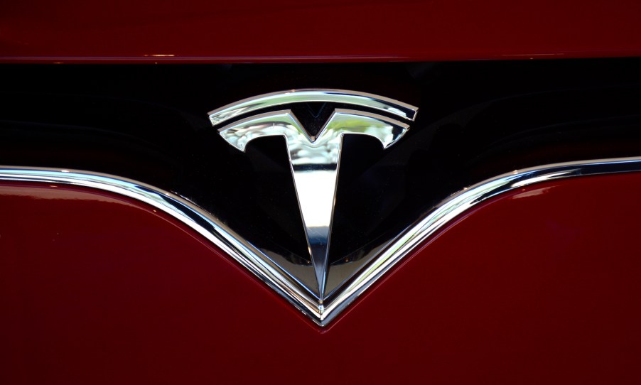 The Tesla logo on the nose of a red electric sedan