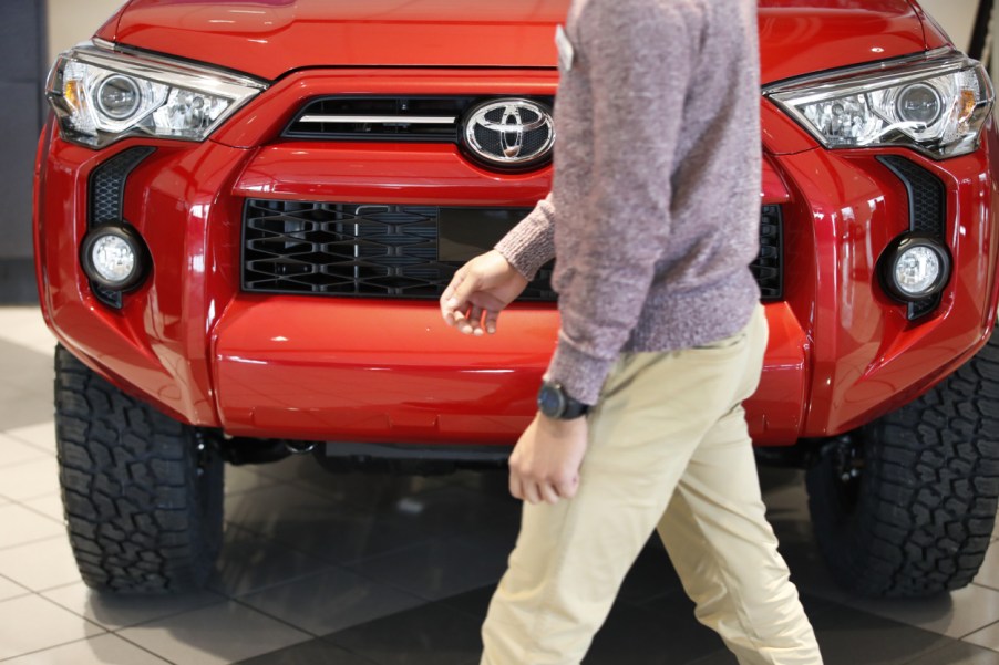 A person walks by a red Toyota 4Runner in a dealership