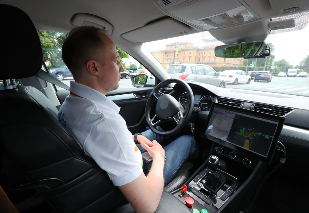 A man sits behind the wheel of a StarLine automated car as it undergoes street testing