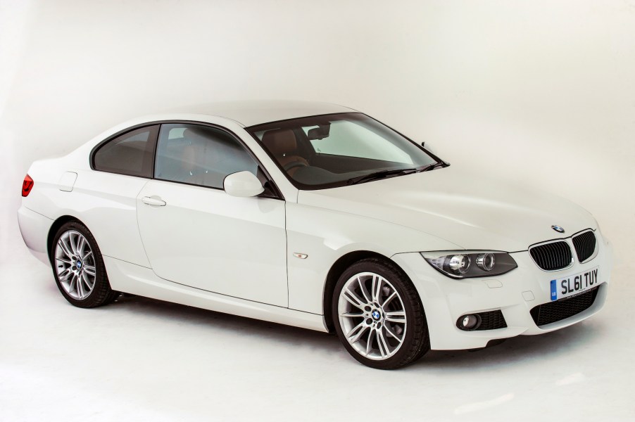 A white 2011 BMW 3 Series coupe in a white studio