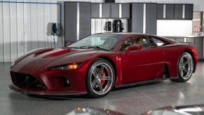 A maroon 2014 Falcon F7 parked in a car garage in front of a silver car