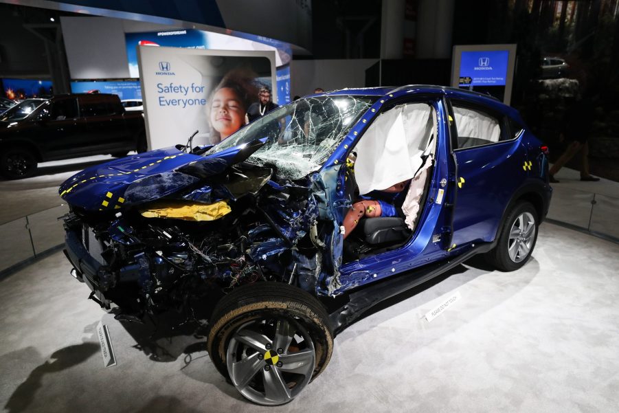 A destroyed blue Honda SUV with a crash-test dummy inside