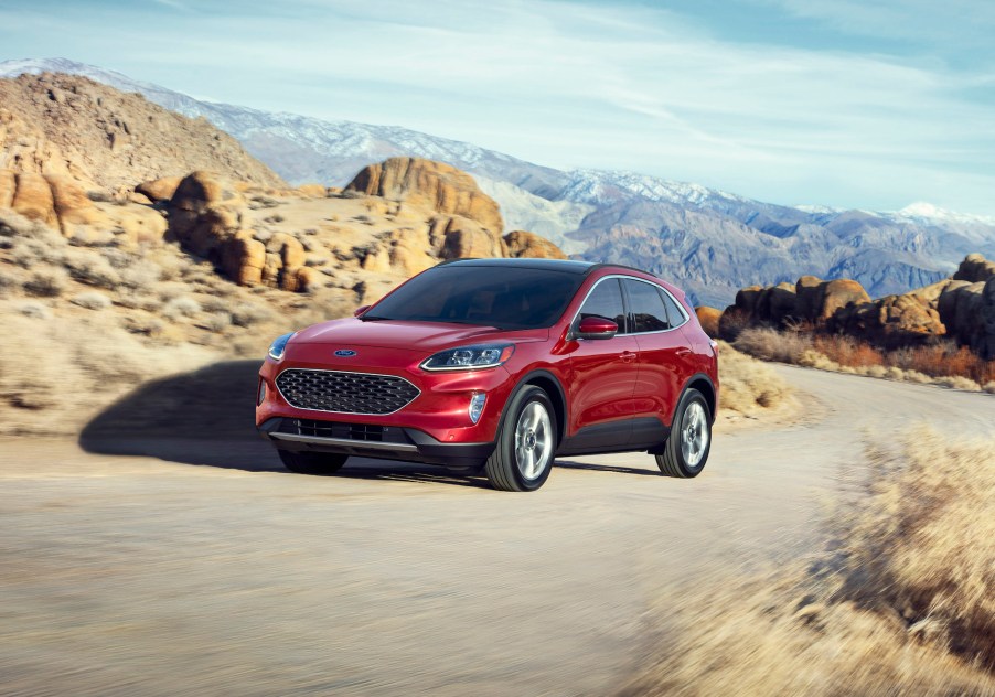 A red 2020 Ford Escape Hybrid compact SUV traveling on a narrow mountain road amid rocky terrain