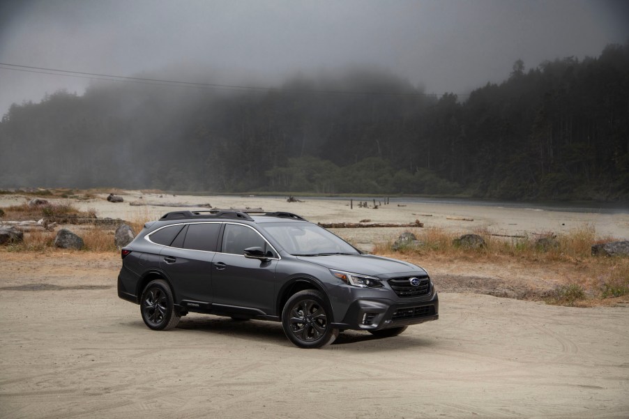 A dark-gray metallic 2020 Subaru Outback crossover SUV parked on a foggy shore