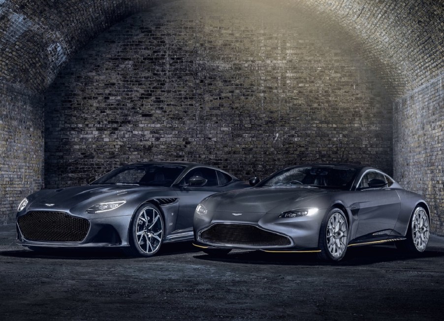 A gray 2021 Aston Martin Vantage 007 Edition and DBS Superleggera 007 Edition by a cobblestone wall