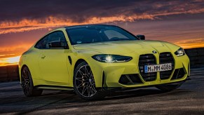 A bright-green 2021 BMW M4 Competition on a racetrack at sunset