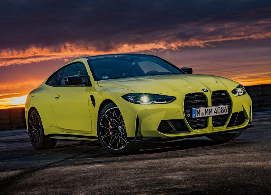 A bright-green 2021 BMW M4 Competition on a racetrack at sunset