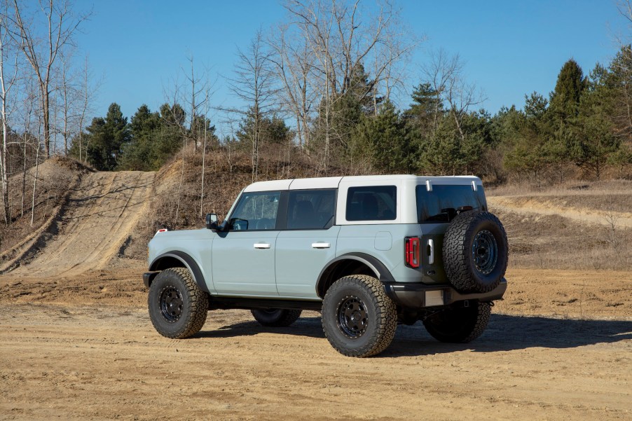 A four-door 2021 Ford Bronco SUV parked on a dirt trail near the woods