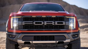 A close-up head-on view of a red 2021 Ford F-150 Raptor full-size pickup truck parked in a mountainous dessert