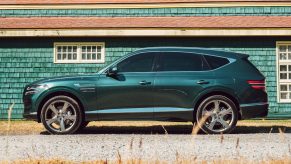 A turquoise 2021 Genesis GV80 parked next to a building