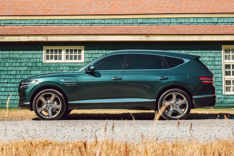 A turquoise 2021 Genesis GV80 parked next to a building