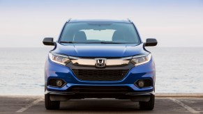 A blue 2021 Honda HR-V subcompact crossover SUV sitting in a parking space in front of an ocean