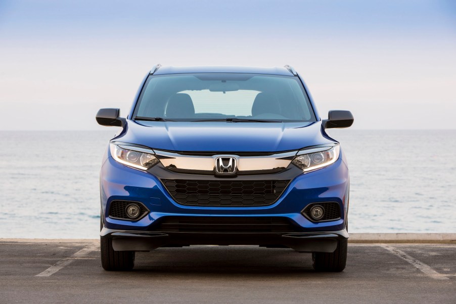 A blue 2021 Honda HR-V subcompact crossover SUV sitting in a parking space in front of an ocean