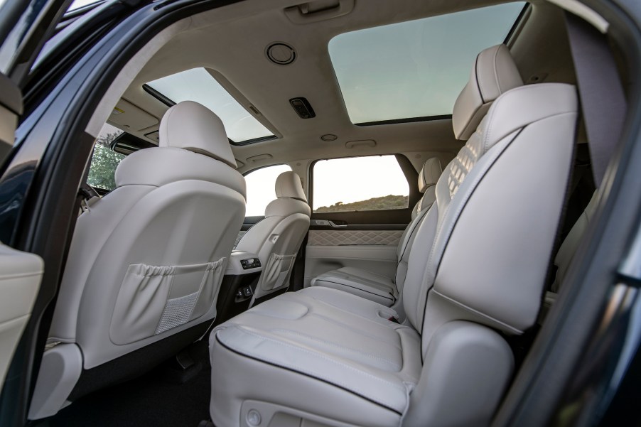 The interior of a 2021 Hyundai Palisade midsize crossover SUV with two moonroofs and quilted white leather seats