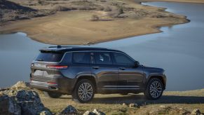 A black 2021 Jeep Grand Cherokee L Summit Reserve parked next to a lake on rugged terrain