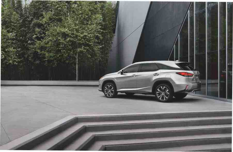 A silver 2021 Lexus RX L midsize luxury SUV parked at the top of some concrete steps next to a modern building and trees