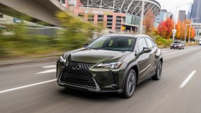 A dark-olive-green 2021 Lexus UX hybrid subcompact crossover SUV drives past CenturyLink Field in Seattle, Washington