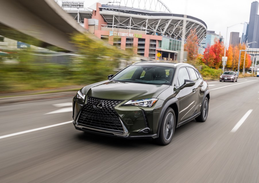 A dark-olive-green 2021 Lexus UX hybrid subcompact crossover SUV drives past CenturyLink Field in Seattle, Washington