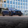 A blue 2021 Mercedes-AMG E63 S Wagon parked on a building's roof in a city