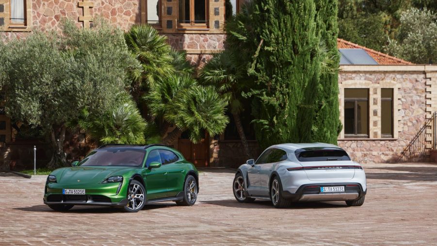 A green 2021 Porsche Taycan Turbo S Cross Turismo next to a rear-facing white Taycan 4S Cross Turismo by a villa