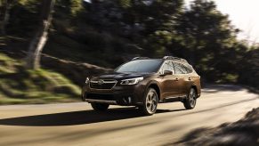 A dark red 2021 Subaru Outback driving down a highway road