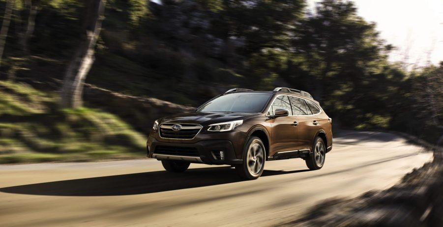 A dark red 2021 Subaru Outback driving down a highway road