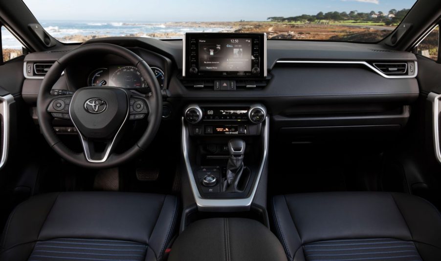 A silver 2021 Toyota RAV4 Hybrid SUV's black dashboard, steering wheel, center stack, and infotainment touchscreen