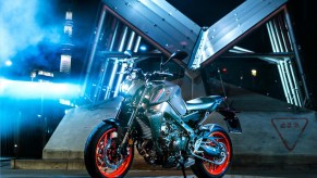 A gray-and-black-with-orange-wheels 2021 Yamaha MT-09 in front of a building at night