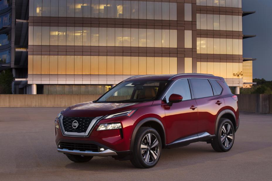 A red Nissan Rogue parked in front of a glass-front administrative building