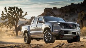 A silver 2022 Nissan Frontier driving on a dirt road