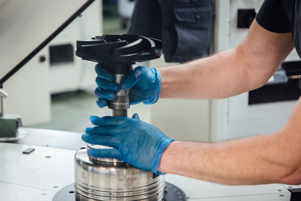 A technician assembles a centrifugal pump impeller on a work bench