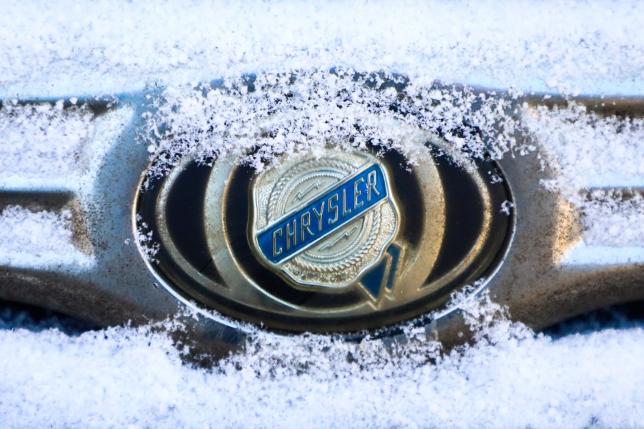 A Chrysler car emblem is covered with snow on a car