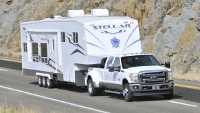 A white Ford F-350 super duty pickup truck towing a camper