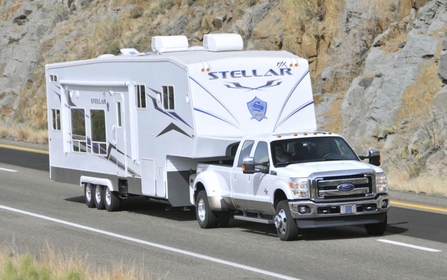 A white Ford F-350 super duty pickup truck towing a camper