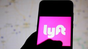 The Lyft logo displayed on a smartphone in a person's left hand