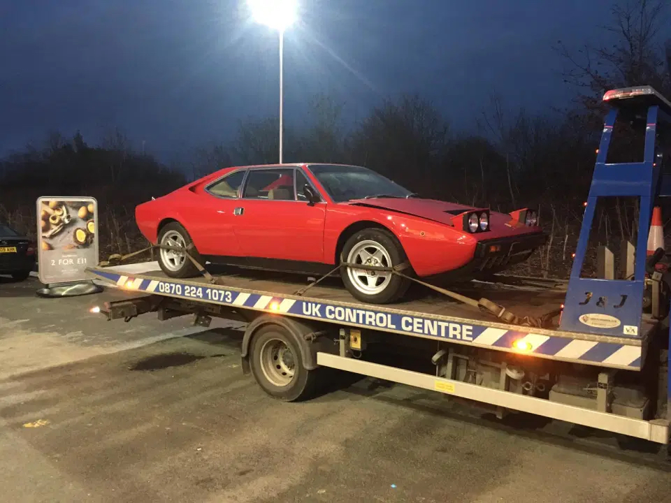 An image of a red Ferrari Dino 308 GT4 parked outdoors.