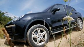 A black Porsche Cayenne driving down a dirt road