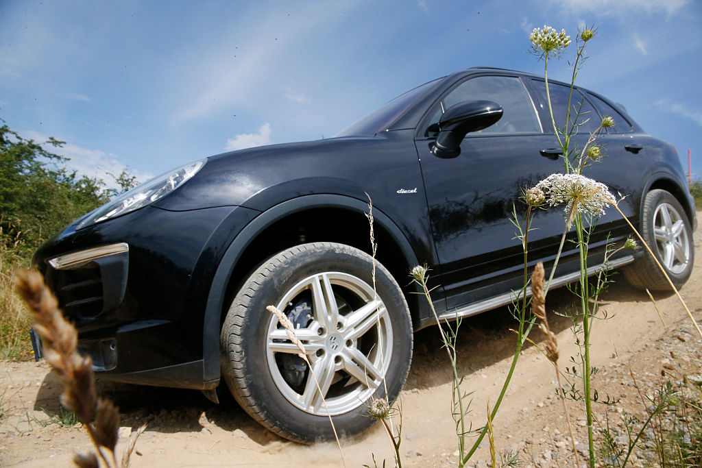 A black Porsche Cayenne driving down a dirt road