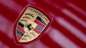 Light reflects off the Porsche logo on a red vehicle